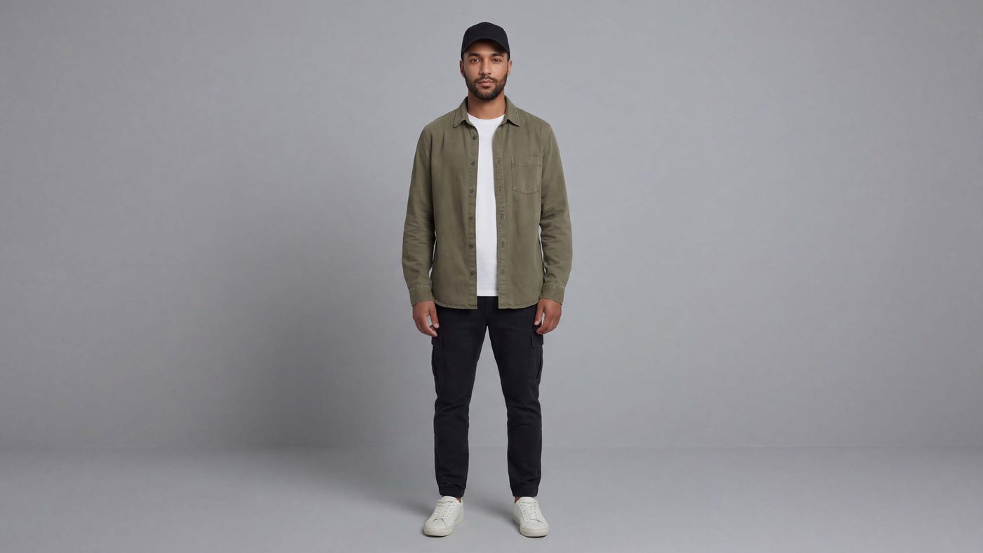 Karim Mansouri in costume: olive jacket, white T-shirt, dark cap